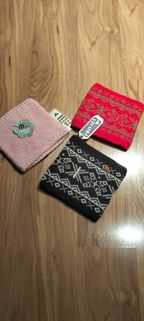 Tres pequeñas carteras de tela estampada en rosa, rojo y negro, sobre un suelo de madera.