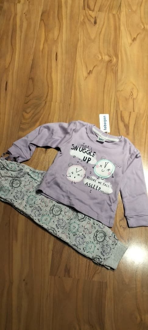 Camisa lavanda de manga larga y pantalones estampados extendidos sobre un suelo de madera