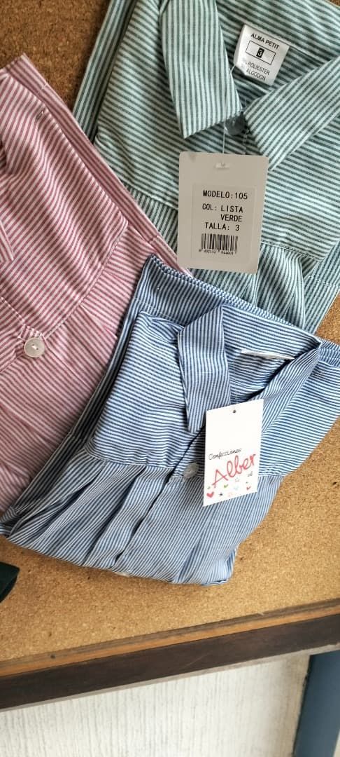 Tres camisas de rayas abotonadas y dobladas, en rosa, verde y azul, sobre una mesa