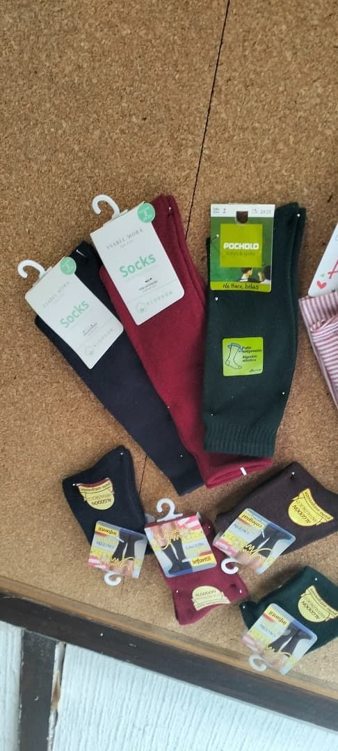 Calcetines navideños variados con etiquetas de producto colgados en un expositor de pared marrón
