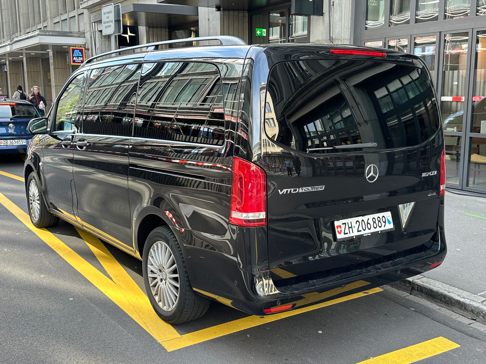 Ein Mann mit Koffer hält am Flughafen ein gelb-schwarzes Taxi an.