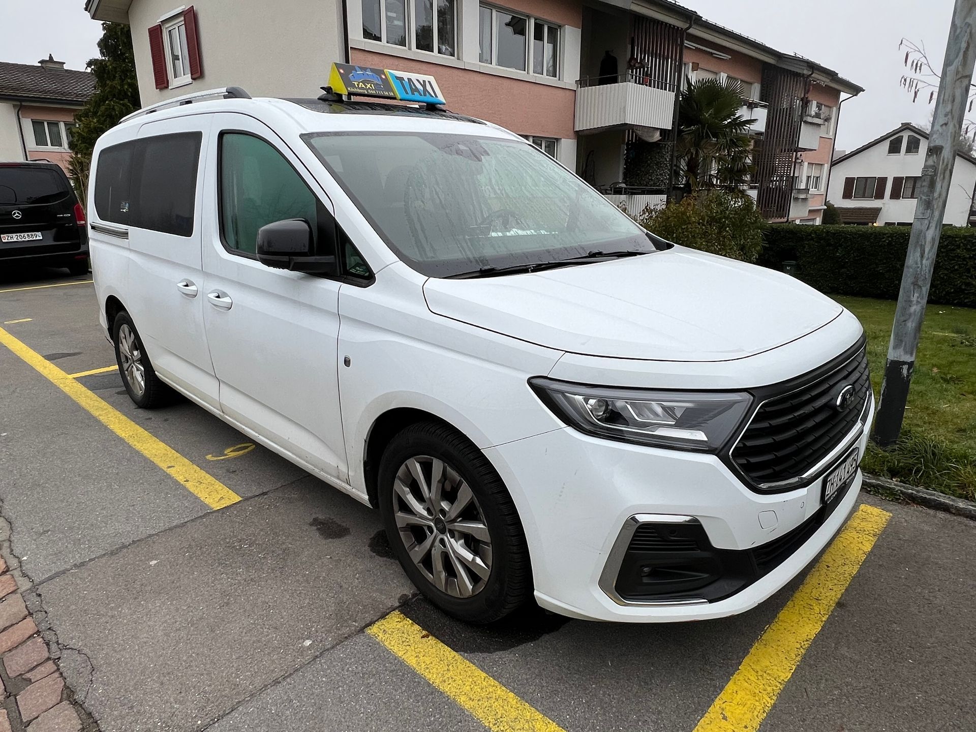 Ein weisser Lieferwagen parkt auf dem Rollfeld eines Flughafens in der Nähe eines Passagierflugzeugs.