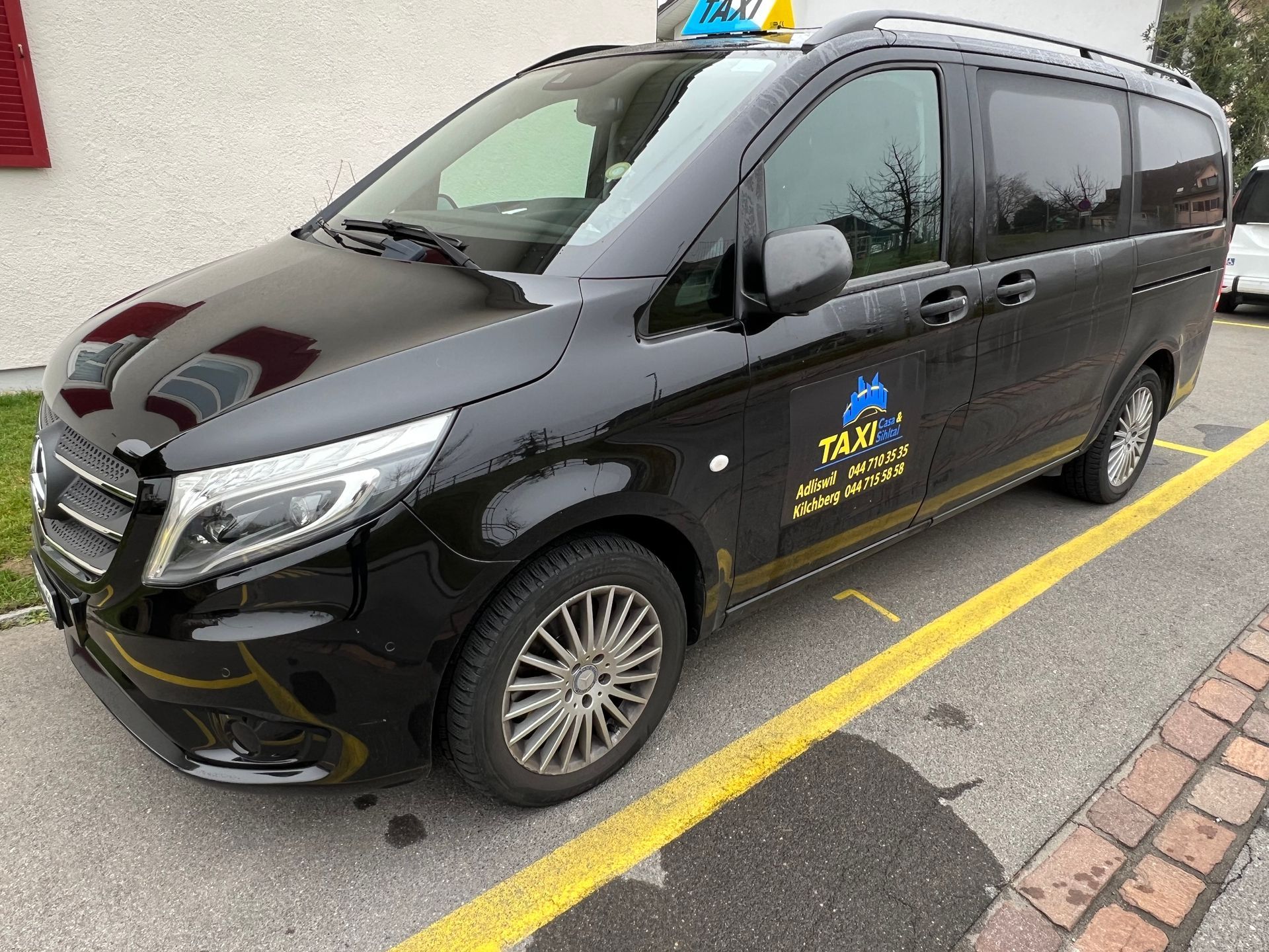 Eine Person im Rollstuhl nähert sich auf einer sonnigen Strasse einem Lieferwagen mit offener Rampe.