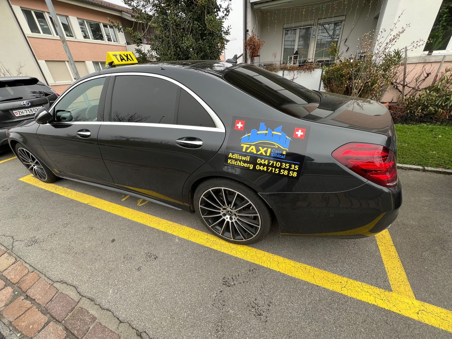 Ein Mann mit Koffer hält am Flughafen ein gelb-schwarzes Taxi an.