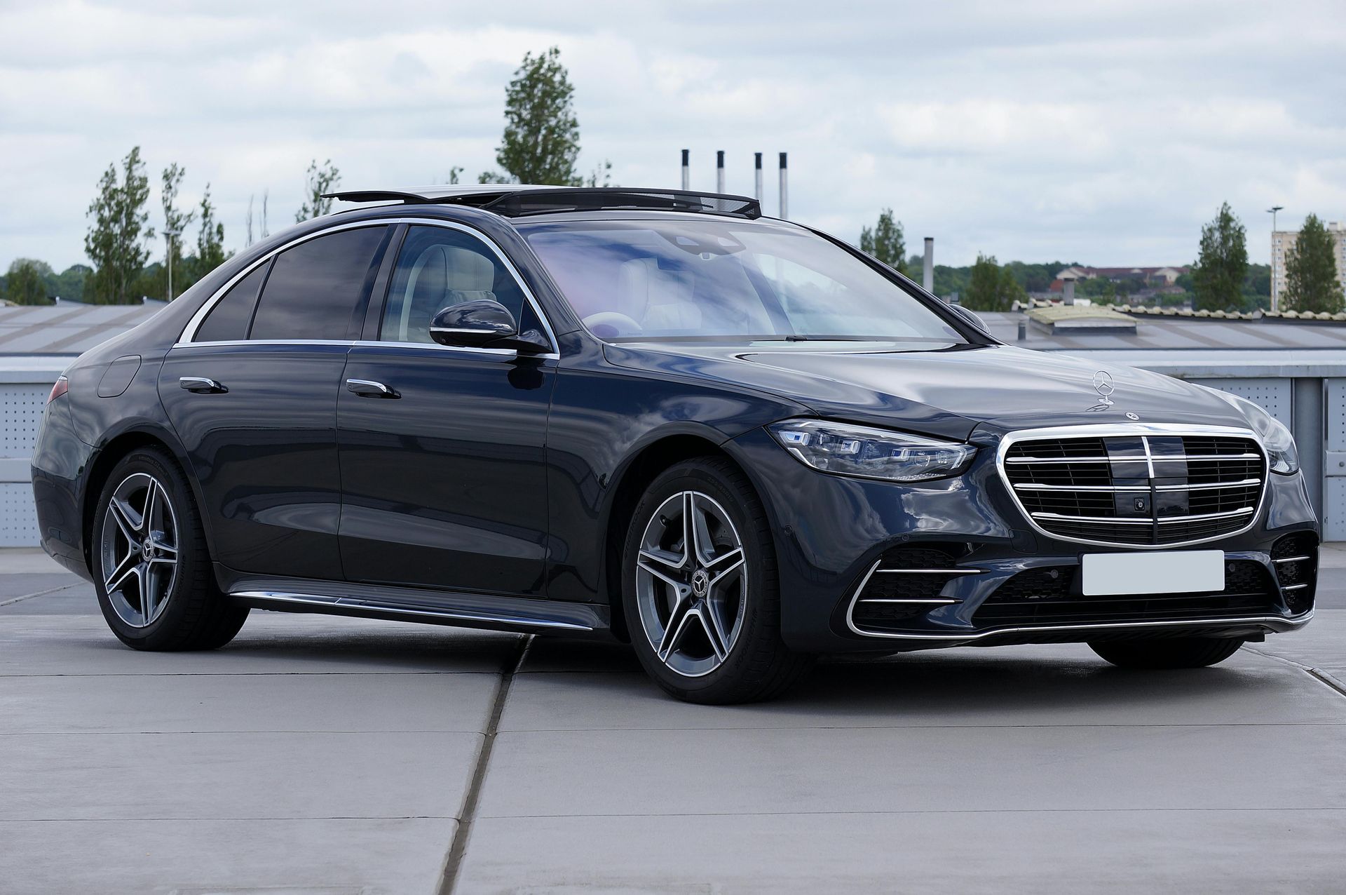 Eine Person im Anzug öffnet die Tür eines schwarzen Autos.