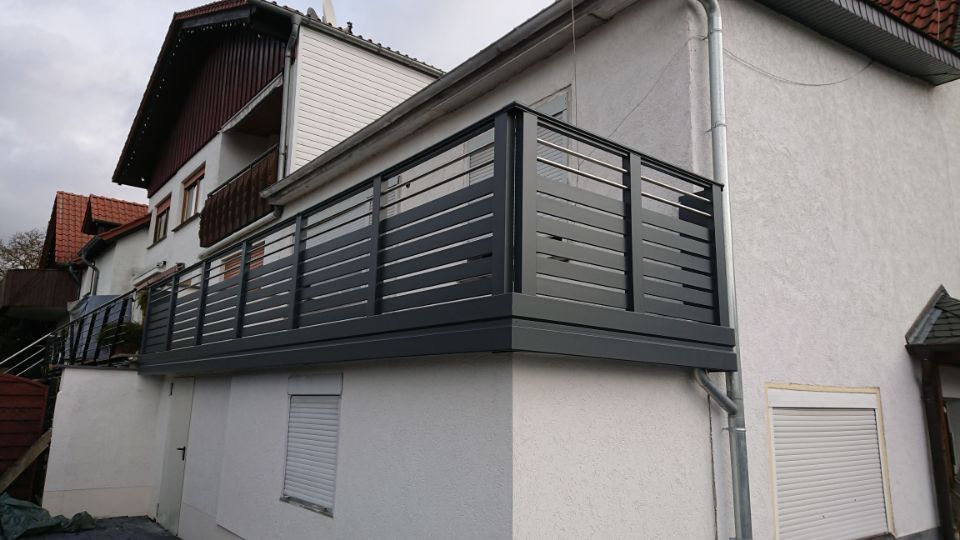 Modernes Hausäußeres mit grauem Balkongeländer und weißen Wänden