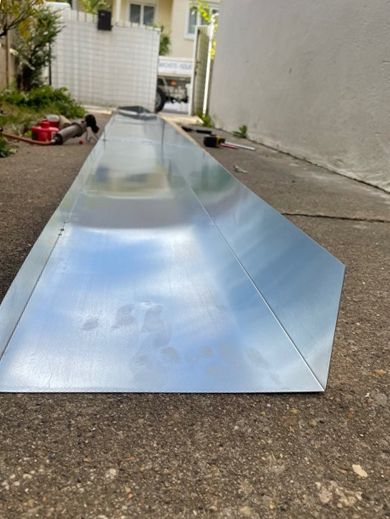 Vue rapprochée d'une plaque de zinc pliée et prête pour installation