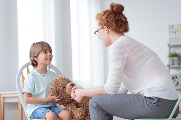 Therapeutin und klein Kind sprechen und arbeiten mit einem Teddy