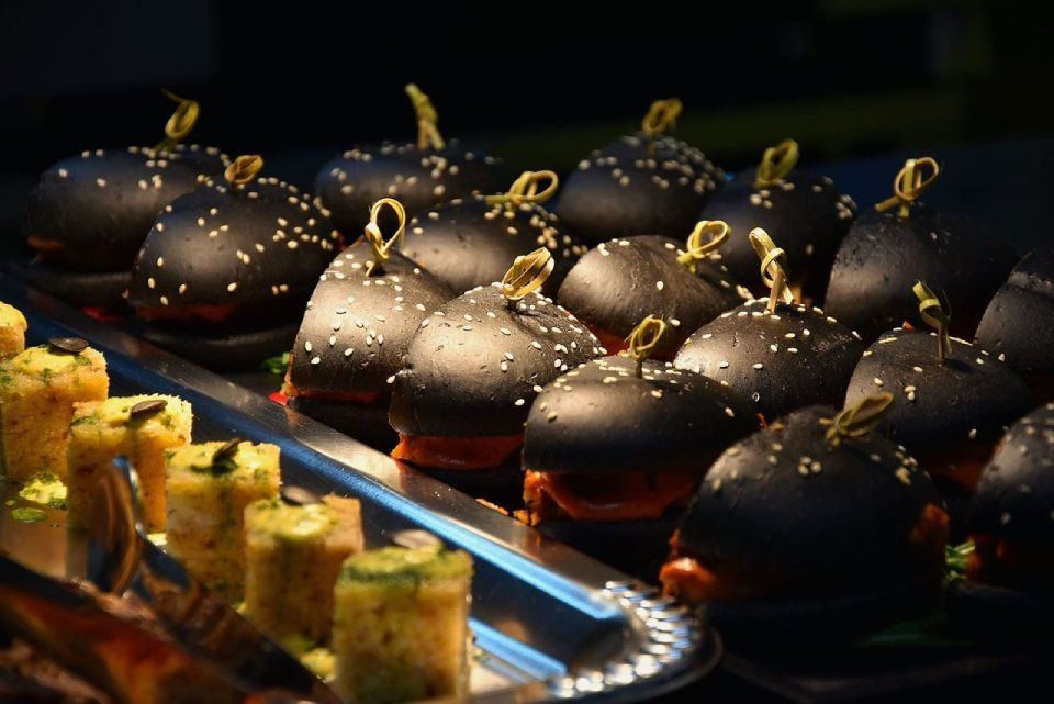 Un tas de hamburgers noirs sont posés sur un plateau.