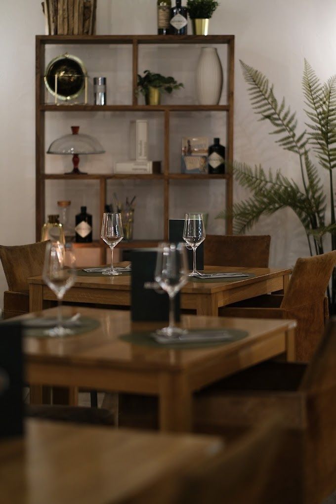 Un restaurant avec des tables, des chaises et des verres de vin dessus.