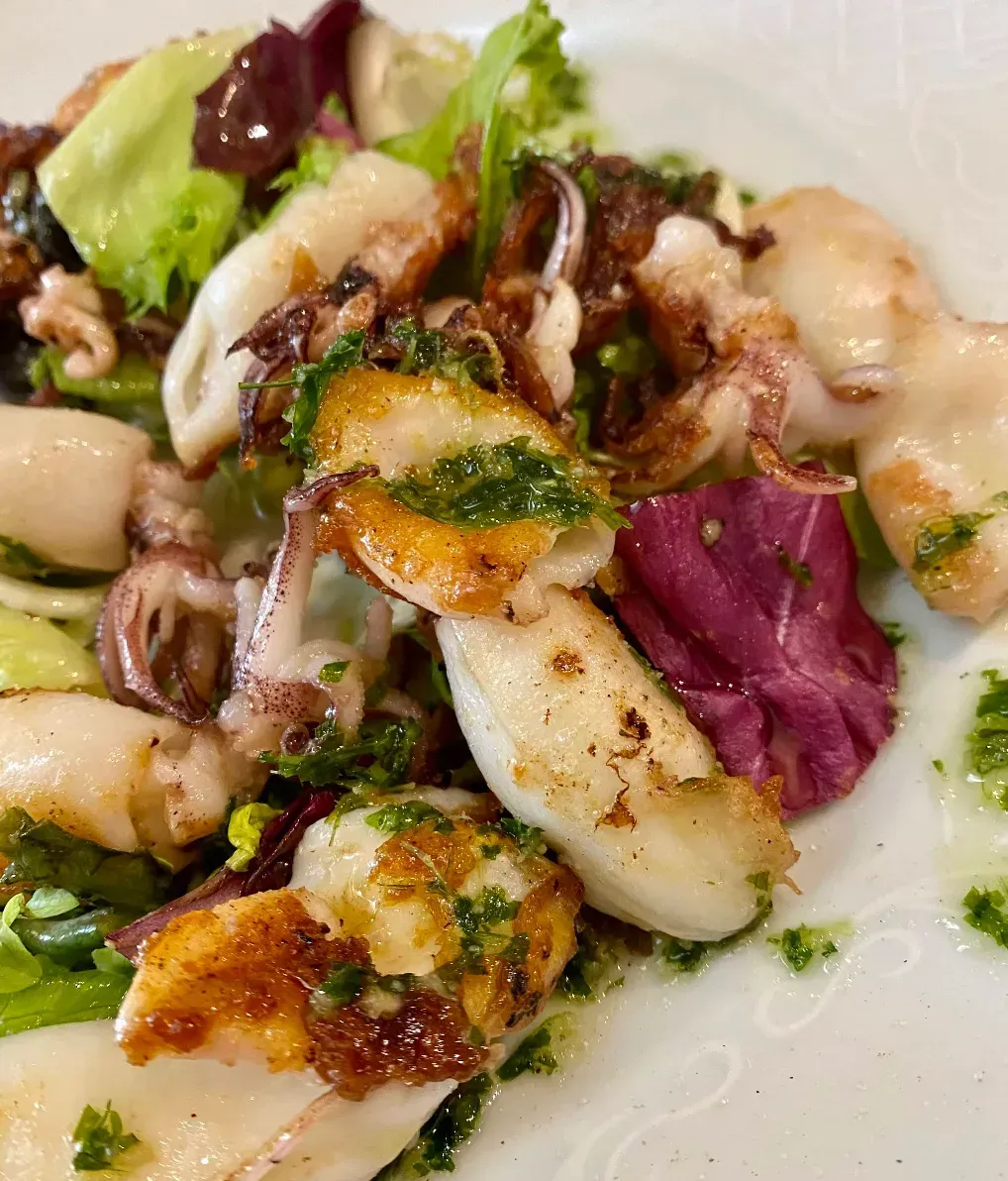 Ensalada de calamares a la plancha con aderezo de verduras y hierbas.