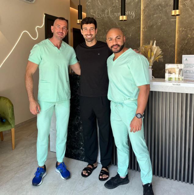 Tres hombres con uniforme médico posan para una fotografía