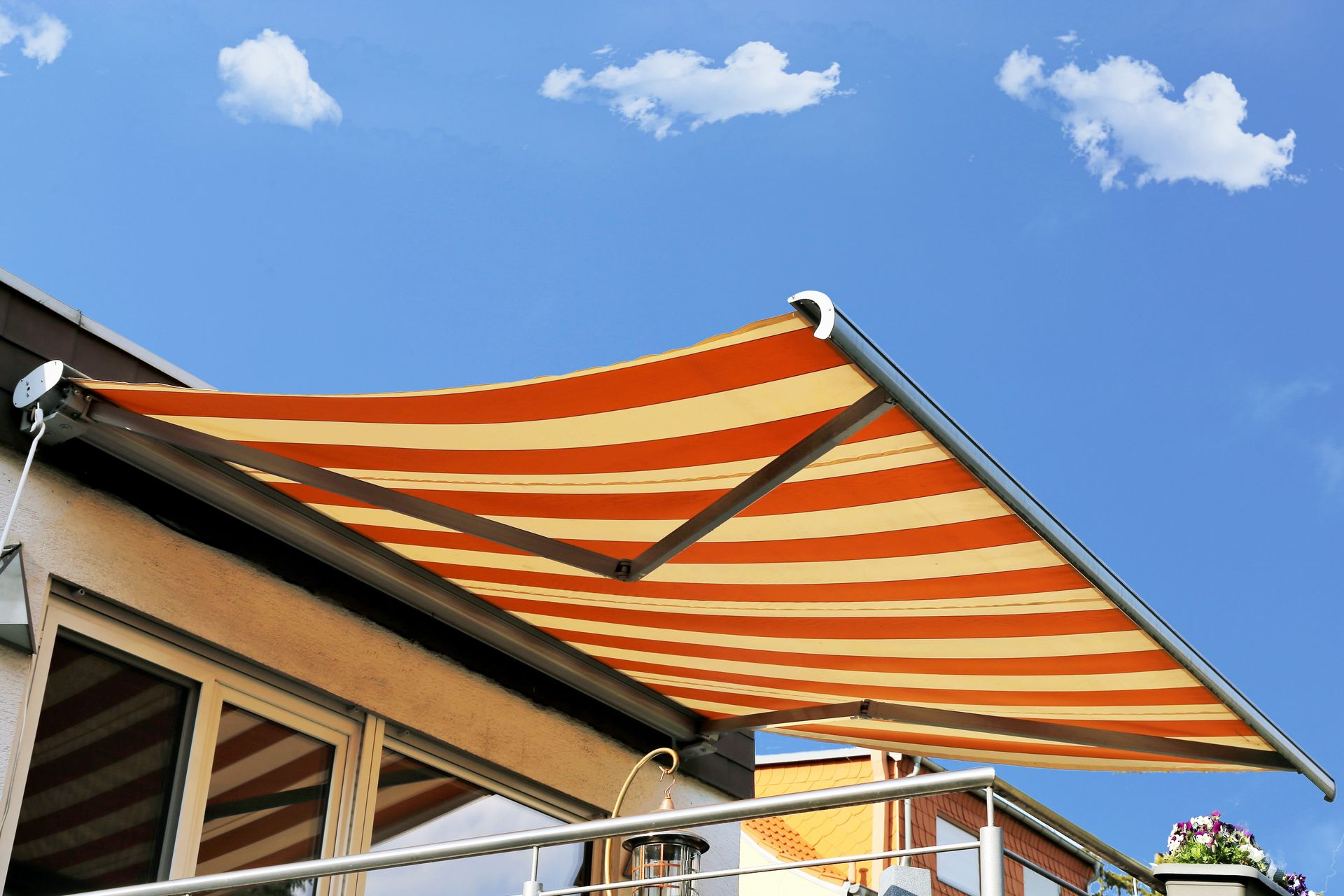 Banne rayée orange et blanche s’avançant depuis un bâtiment sur fond de ciel bleu