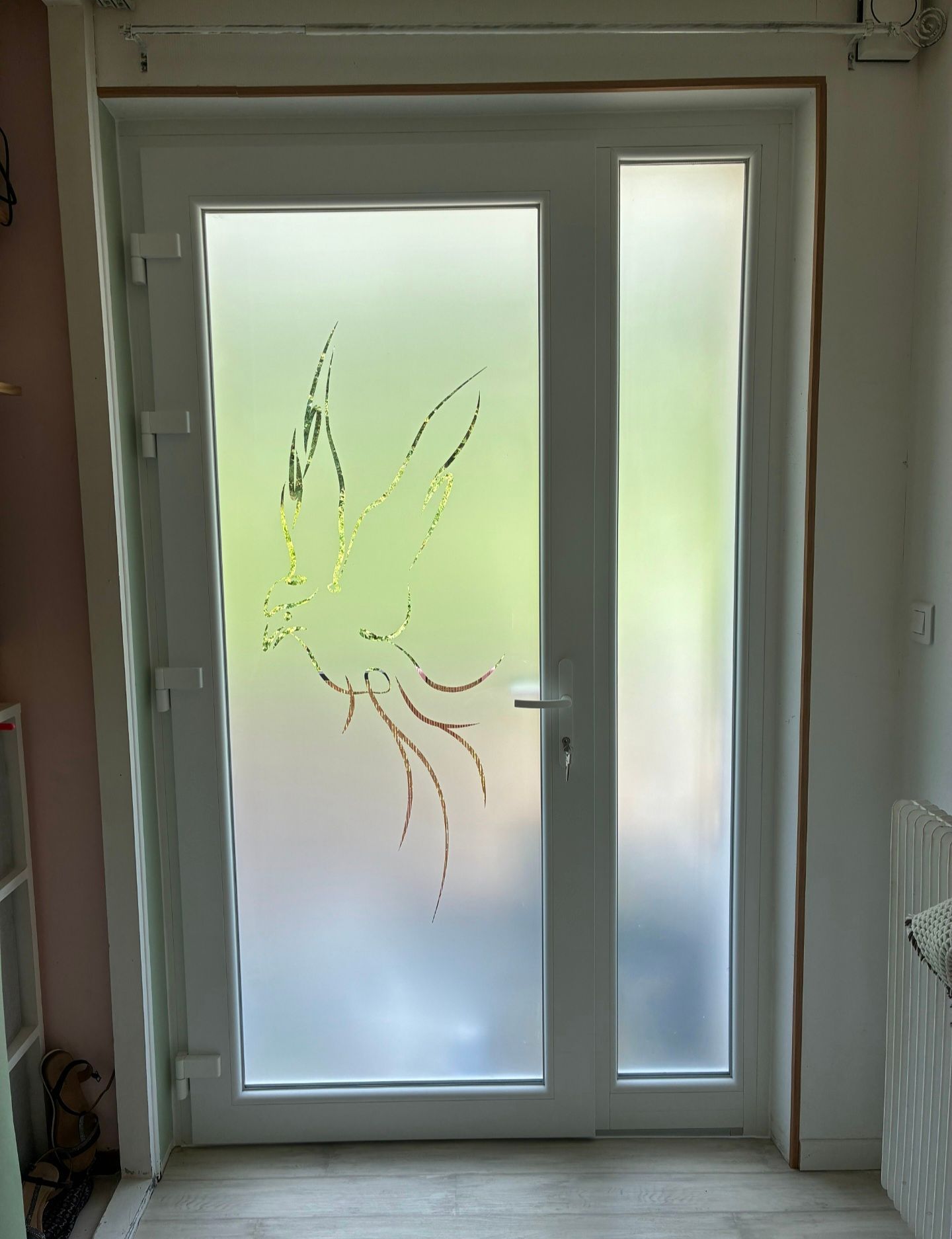 Porte d’entrée avec panneaux en verre dépoli et motif floral gravé dans un couloir