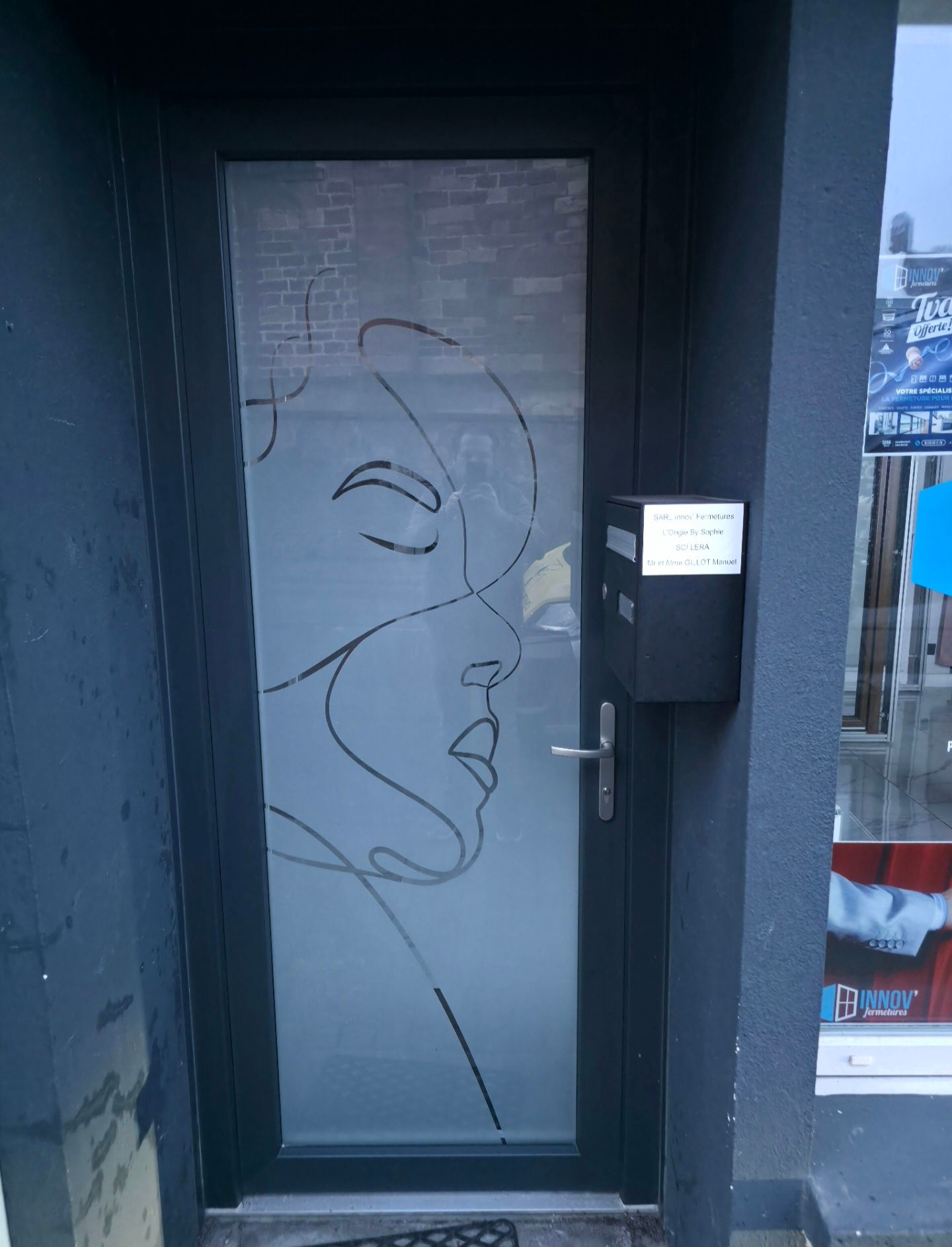 Porte en verre dépoli avec un dessin de visage au trait et un clavier à code à côté