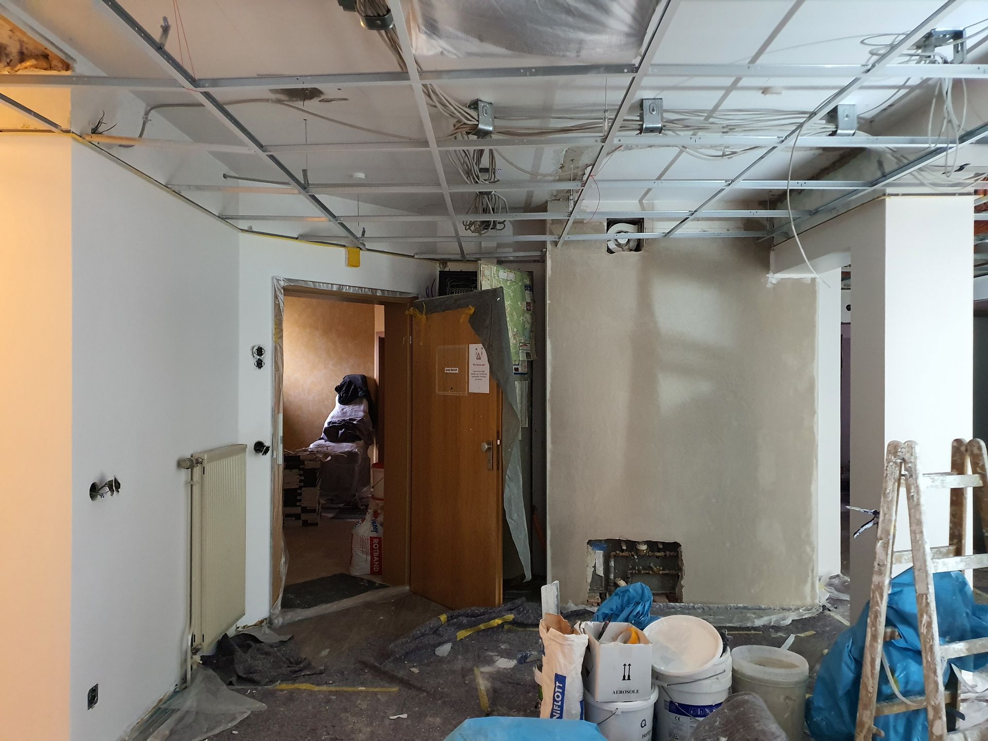 Ein Raum mit einer Tür und einer Leiter darin wird umgebaut.