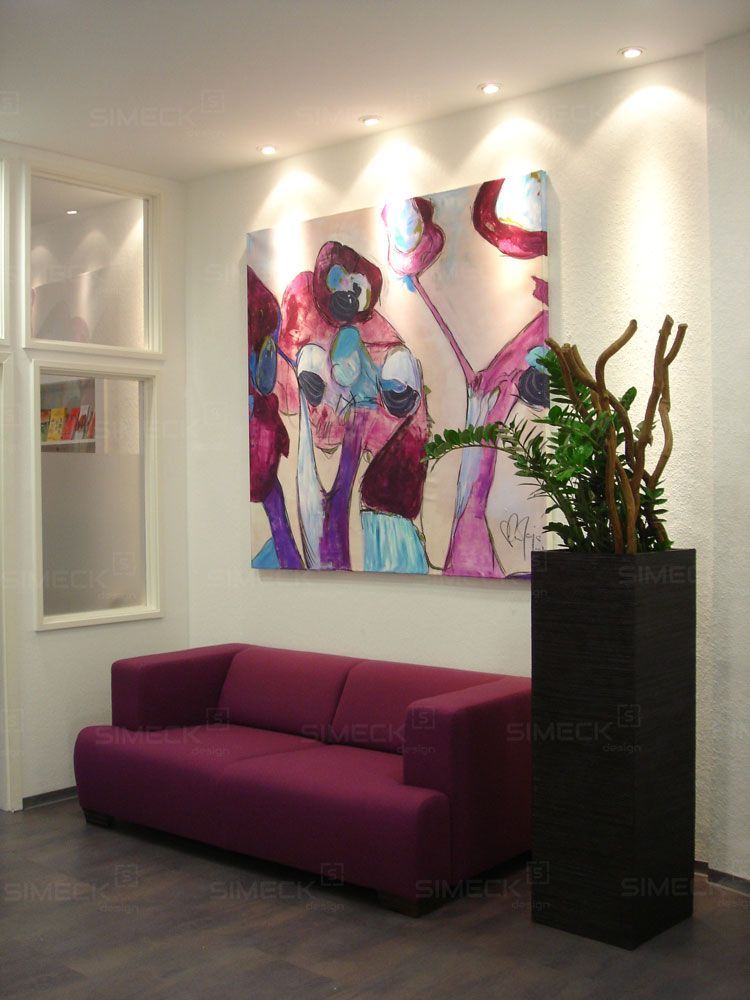 Ein Wohnzimmer mit einem lila Sofa und einem Gemälde an der Wand