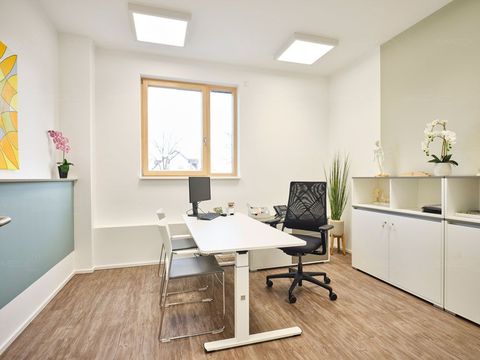 Ein kleines Büro mit einem Schreibtisch, Stühlen und einem Fenster.