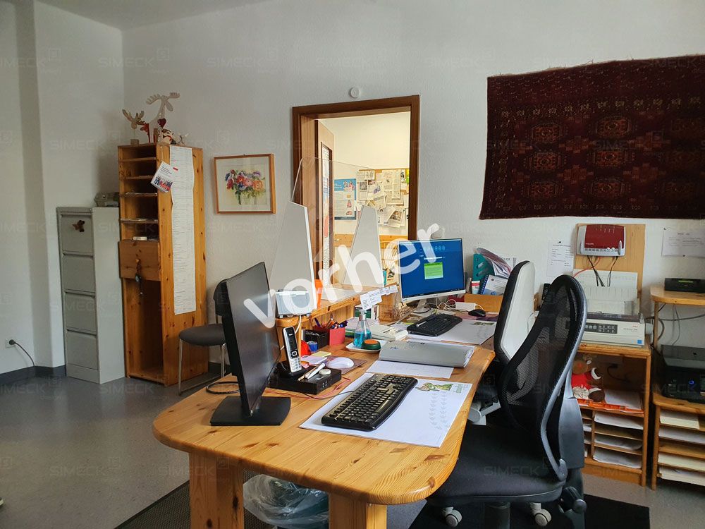 Ein Zimmer mit einem Schreibtisch und Stühlen und dem Wort „Vorher“ an der Wand