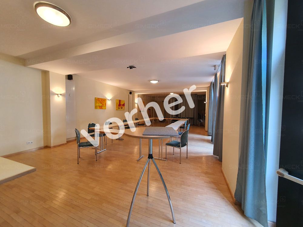 Ein großer leerer Raum mit einem Tisch und Stühlen darin.