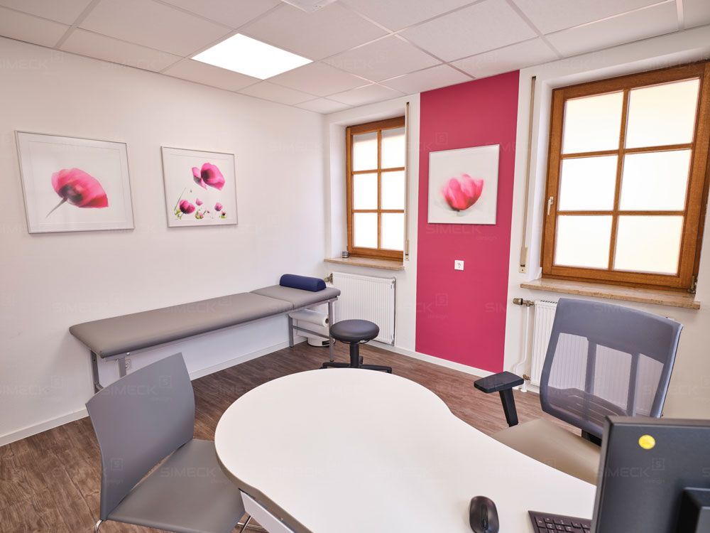 Eine Arztpraxis mit einem Tisch und Stühlen und einer rosa Wand