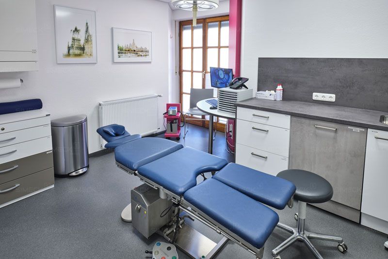 Ein Operationssaal mit einem blauen Operationstisch und einem Hocker.