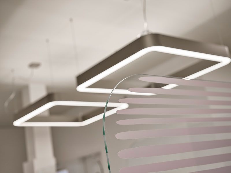 In einem Raum hängen drei quadratische Lichter von der Decke