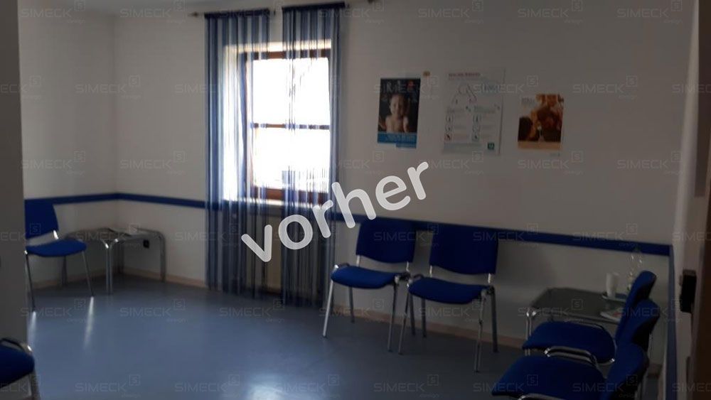 Ein Wartezimmer mit blauen Stühlen und einem Fenster.