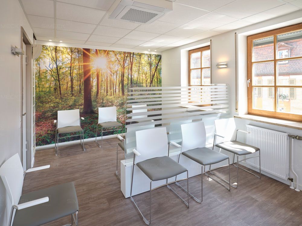 Ein Wartezimmer mit Stühlen und einem Waldbild an der Wand.