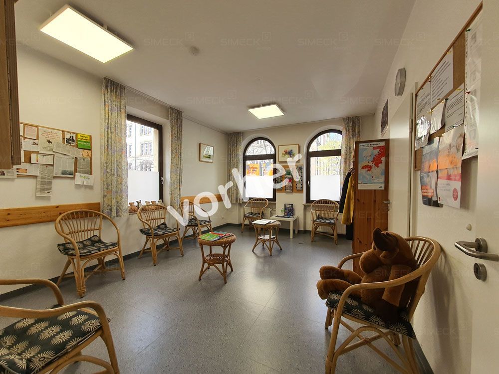 Ein Wartezimmer mit Stühlen und einem Teddybär darin