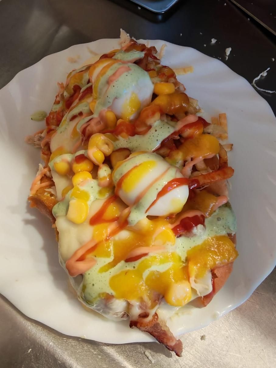 Nachos con queso fundido, maíz y salsas, servidos en un plato blanco.