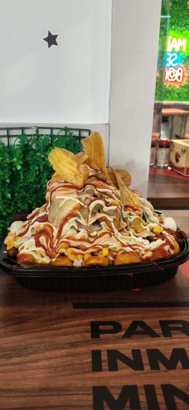 Plato grande de fideos con ingredientes fritos servido en una mesa de madera en un restaurante.