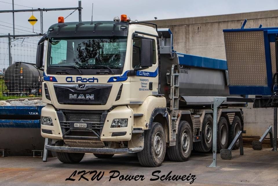 Camion-benne DAF blanc avec remorque bleue sur un chantier.
