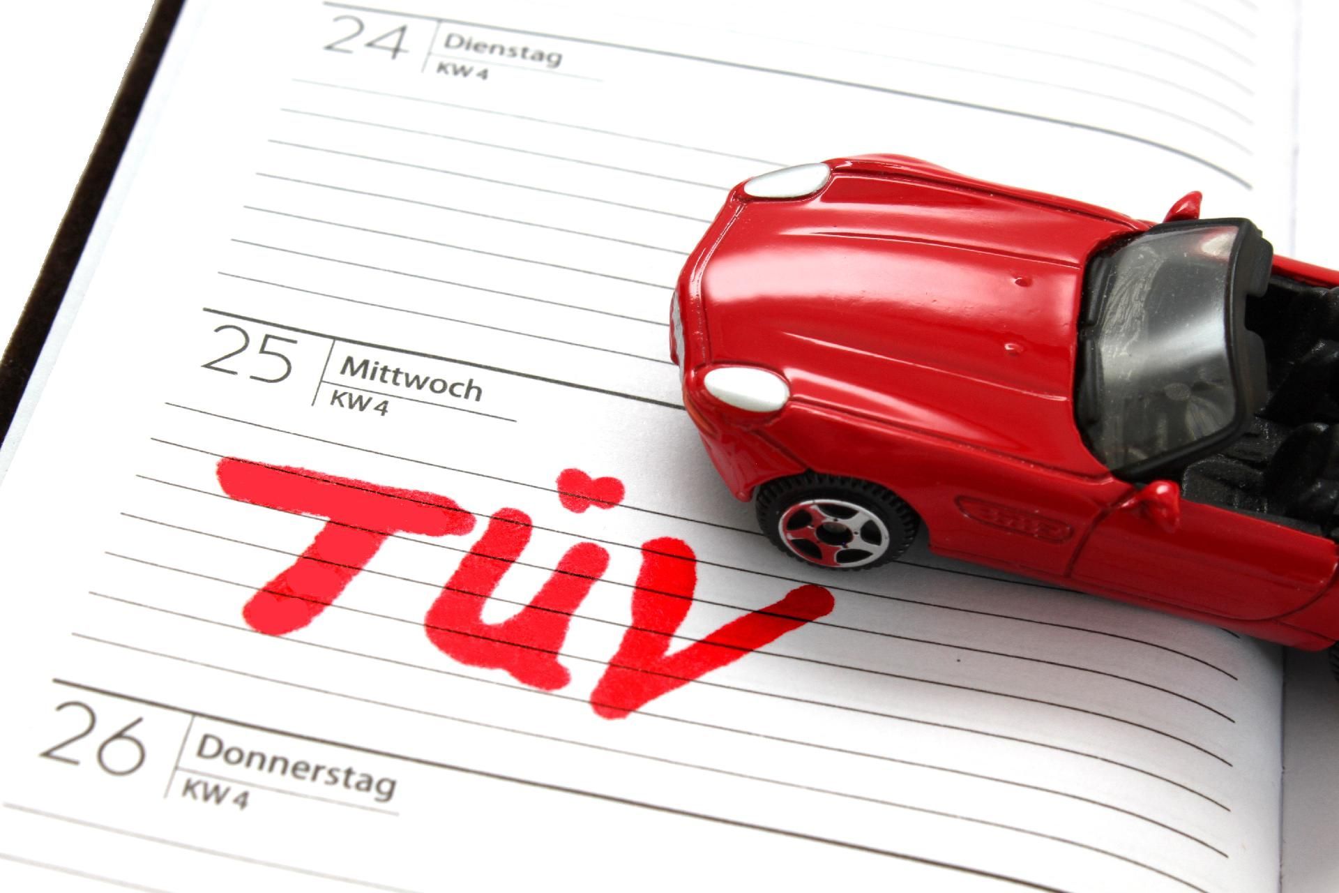 Ein rotes Spielzeug-Cabrio auf einem Kalender mit dem roten Schriftzug „TÜV“.