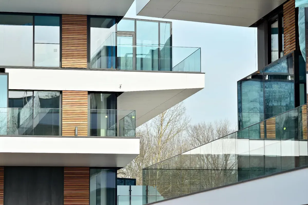 Moderne Gebäudefassade mit Glasbalkonen und Holzvertäfelung.
