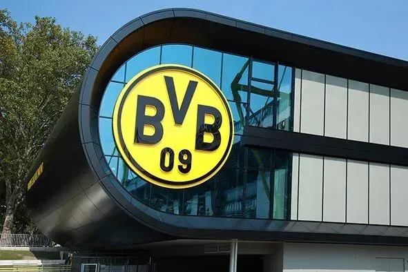 BVB 09-Logo auf einem modernen, geschwungenen Gebäude mit Glasfenstern; gelb-schwarzes Farbschema.
