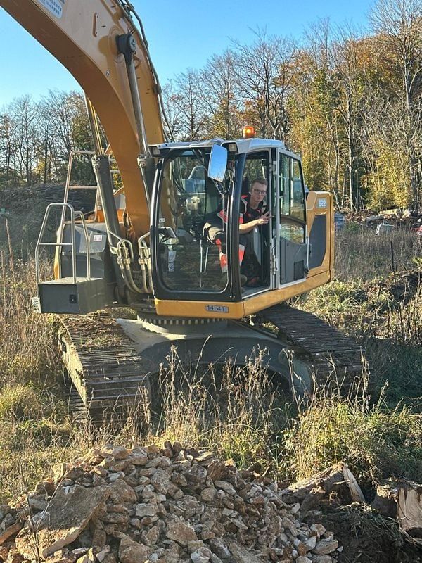 Une excavatrice avec une personne dans la cabine sur un chantier de construction.