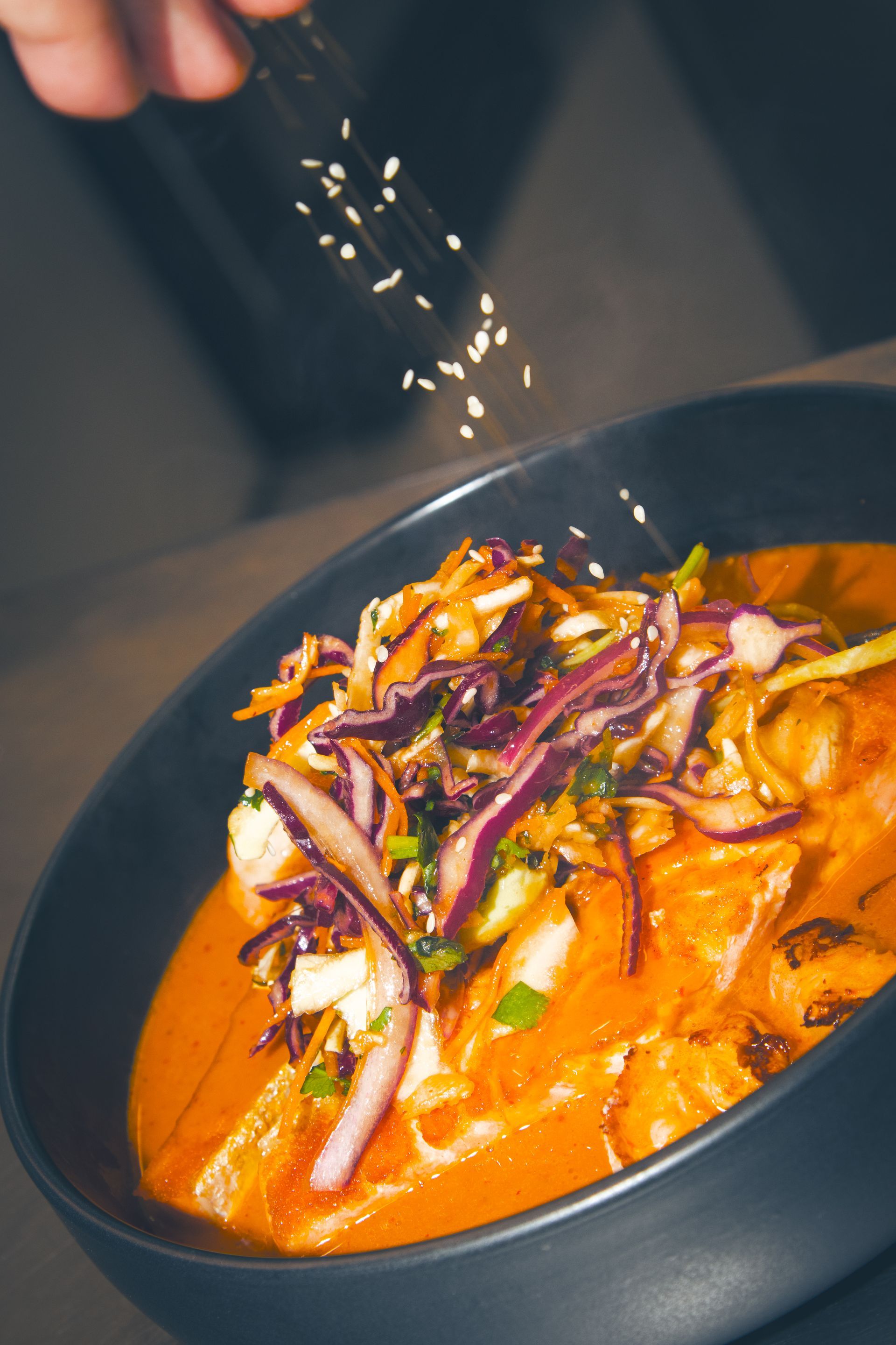 Kulhollinen currynuudeleita grillatun kanan, keitetyn kananmunan, yrttien ja punaisen chilin kera, lusikka kyljessä