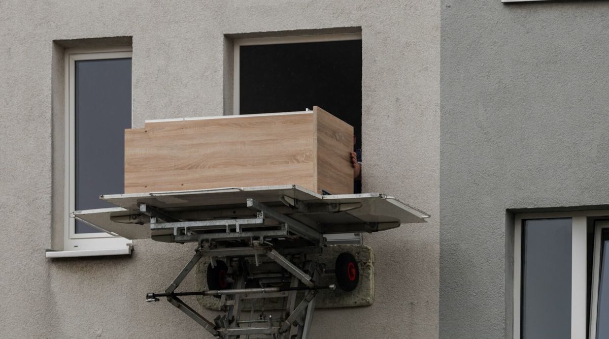 Auf einem Aufzug vor einem Gebäude steht eine Holzkiste.