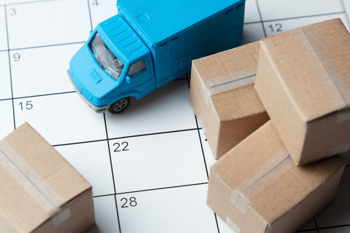 Ein blauer Spielzeuglastwagen steht auf einem Kalender, umgeben von Pappkartons.