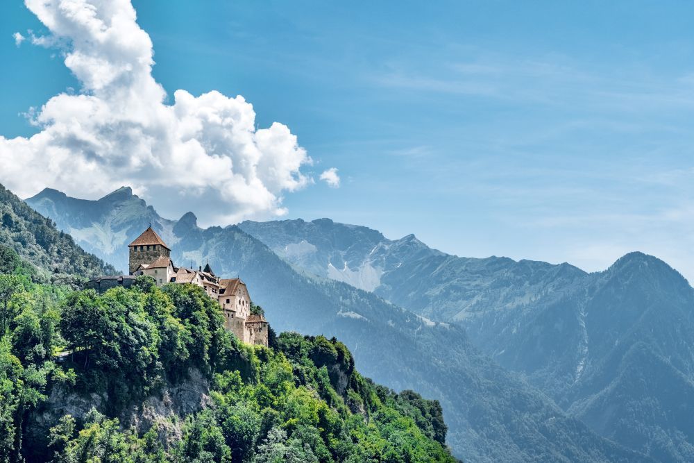 Schloss Vaduz mit Bergen im Hintergrund als Symbolbild für einen Umzug von der Schweiz nach Liechtenstein.