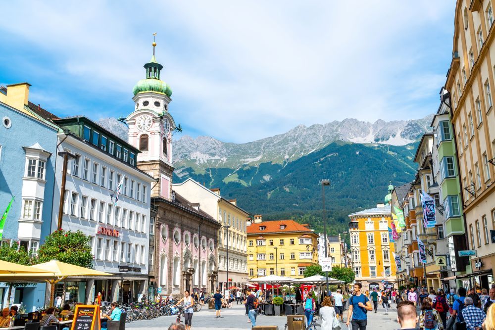 Die Innenstadt von Innsbruck mit Bergen im Hintergrund als Symbolbild für einen Umzug von der Schweiz nach Österreich.