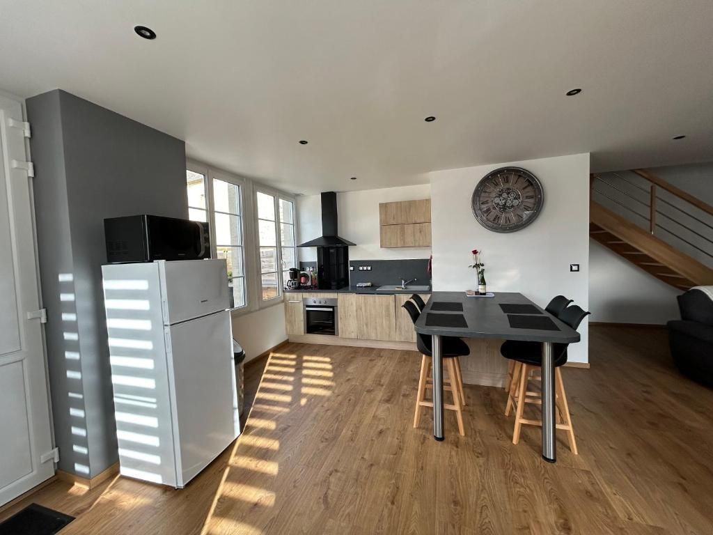 Cuisine avec réfrigérateur, table, cuisinière et escalier.