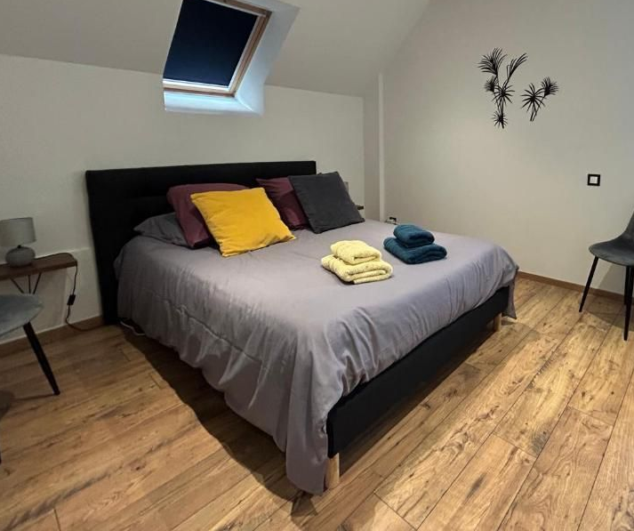 Chambre avec un lit, des oreillers, des serviettes, une lucarne, des œuvres d'art et du parquet.