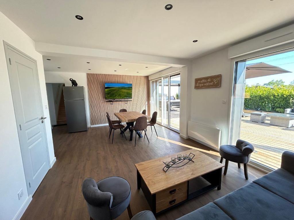 Spacieux salon moderne avec coin repas, touches de bois et accès au patio.