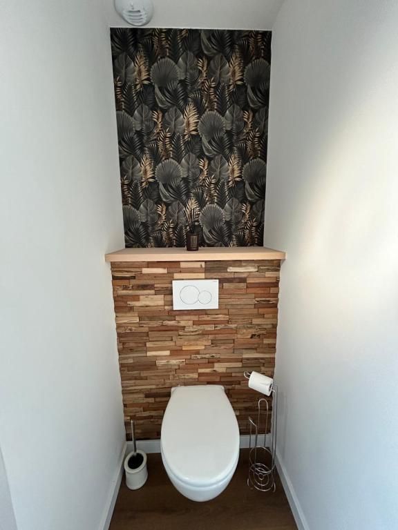 Toilettes dans une petite pièce avec des accents de bois et de papier peint à motifs.