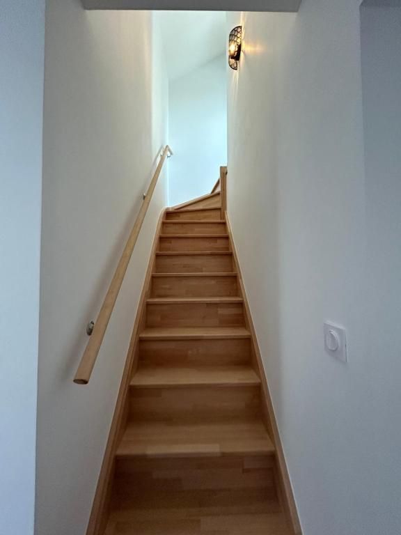 Escalier avec marches en bois et rampe, menant vers le haut avec un luminaire au sommet.