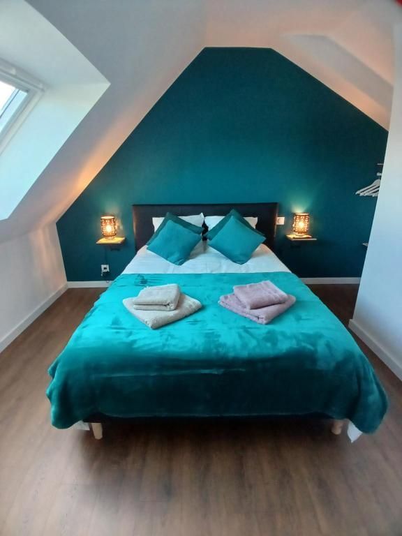 Chambre bleu sarcelle avec lit, oreillers, couvertures et mur d'accent. Deux tables de chevet avec lampes de chaque côté du lit.