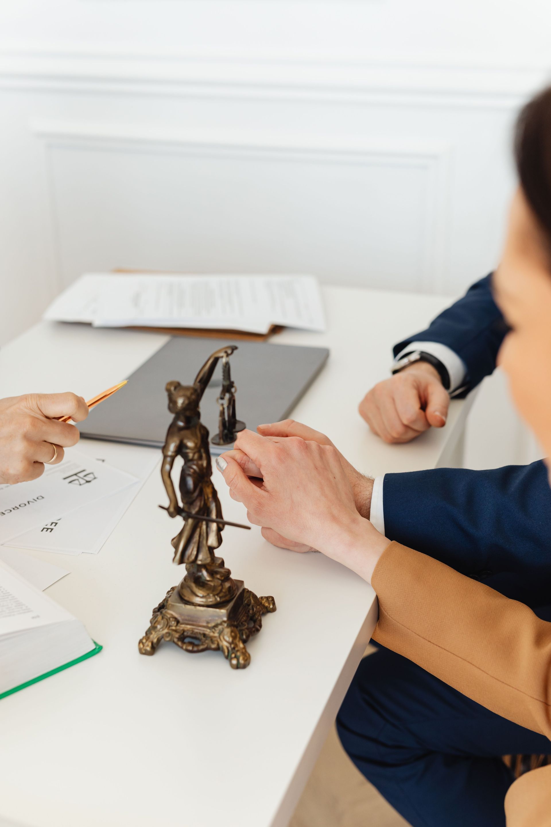 Personas sentadas a una mesa examinando una pequeña figurilla de bronce y unos papeles.