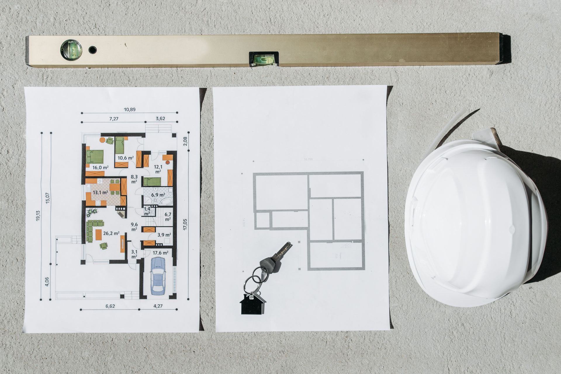 Planos arquitectónicos, herramientas de dibujo y un casco blanco sobre un escritorio.